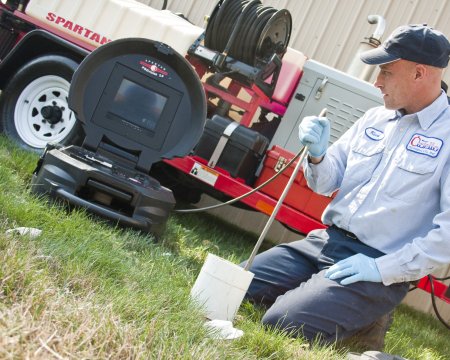 plumber lowering camera into sewer pipe