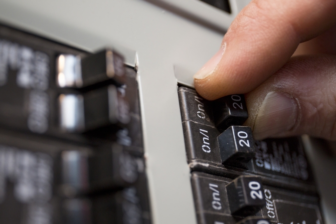 hand switching off an electrical circuit breaker