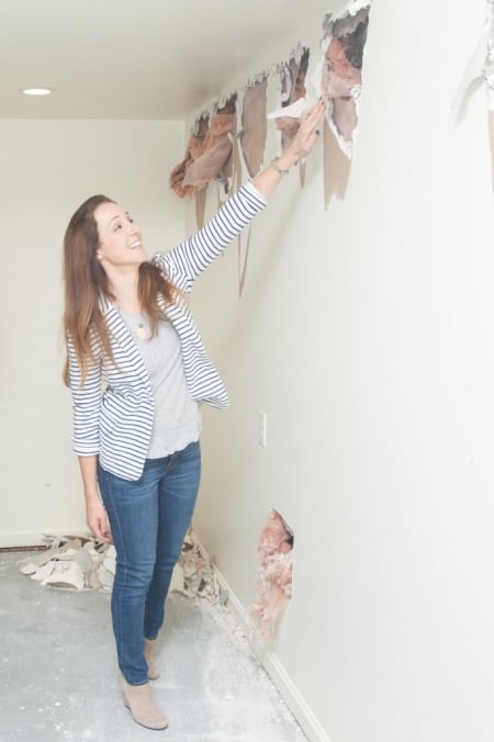 woman standing next to torn-up wall