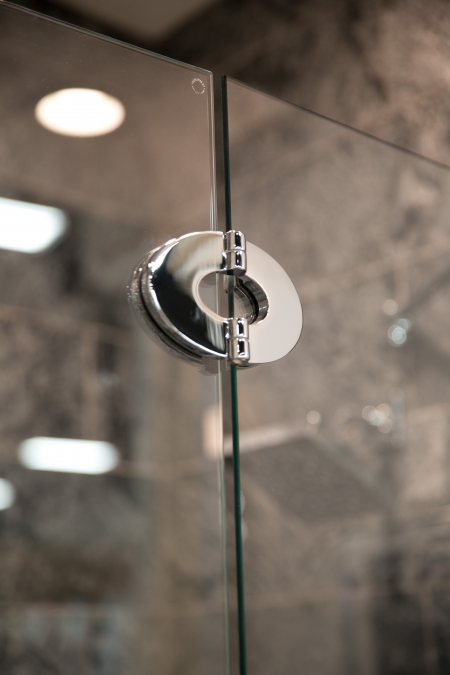 close up of frameless shower door and hinge