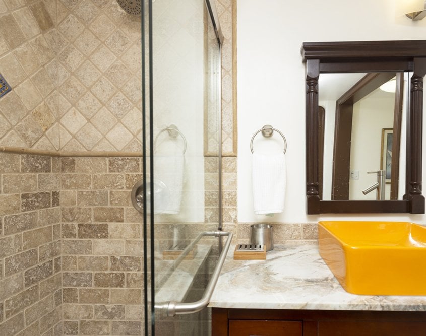 Travertine tile shower and marble countertop in bathroom