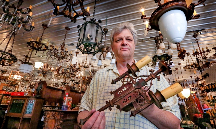 antique store owner holding a light fixture (Photo by Frank Espich)