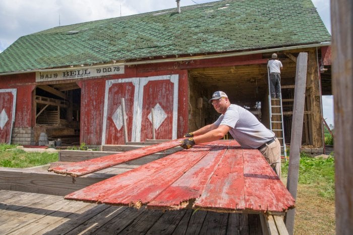 Hoosier Reclaimed Timber owner Adam Dick stacks wood from a barn in Kokomo, Indiana