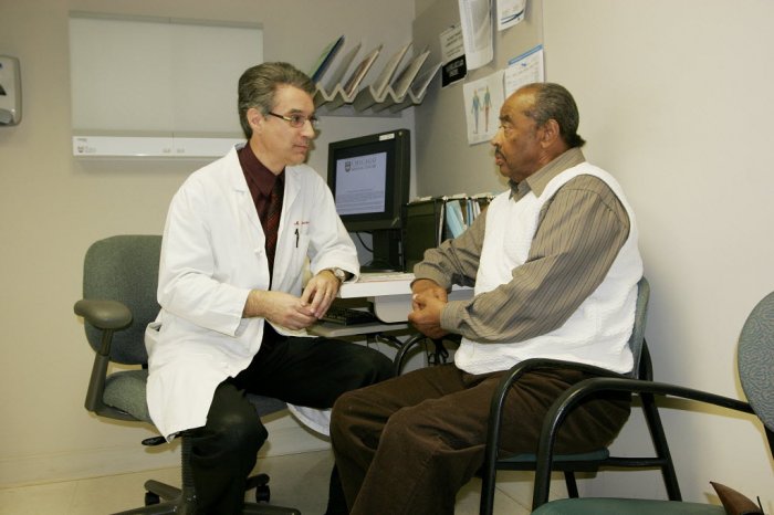 senior man talks with doctor in white coat at doctor's office.
