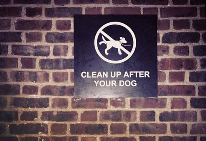 clean up after your dog sign on brick wall