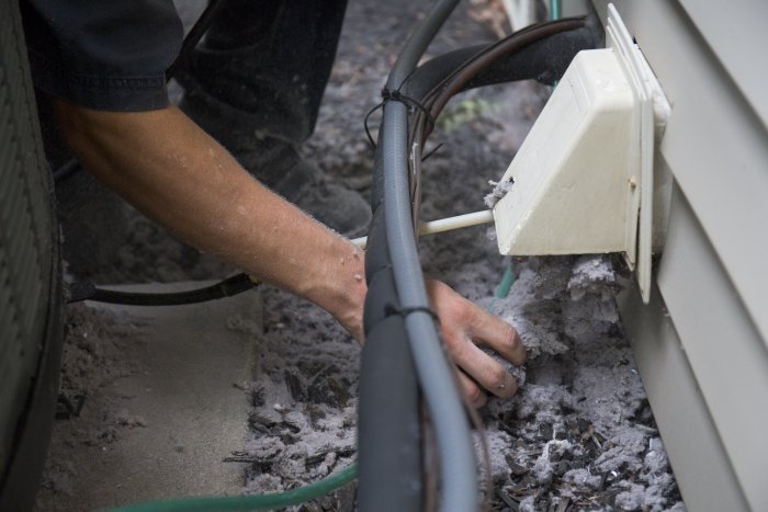 technician clearing lint and debris from outside dryer vent