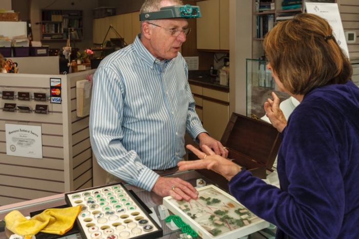 A jeweler appaises some jewelry for a customer.