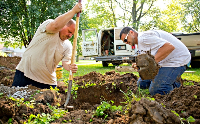 men digging trench in lawn