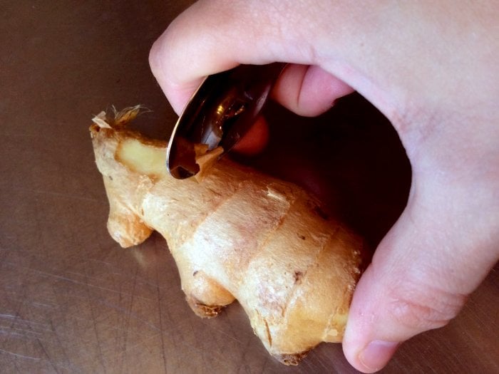 using spoon to peel ginger root