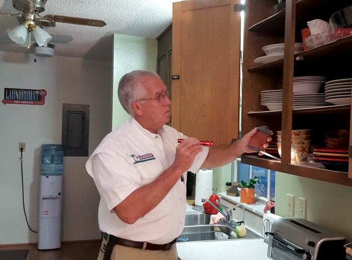 man holding flashlight and inspecting kitchen cabinet