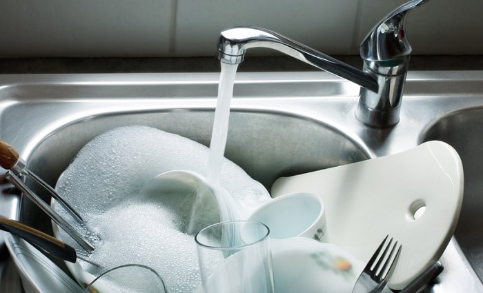 sink full of soapy dishes with water running from faucet