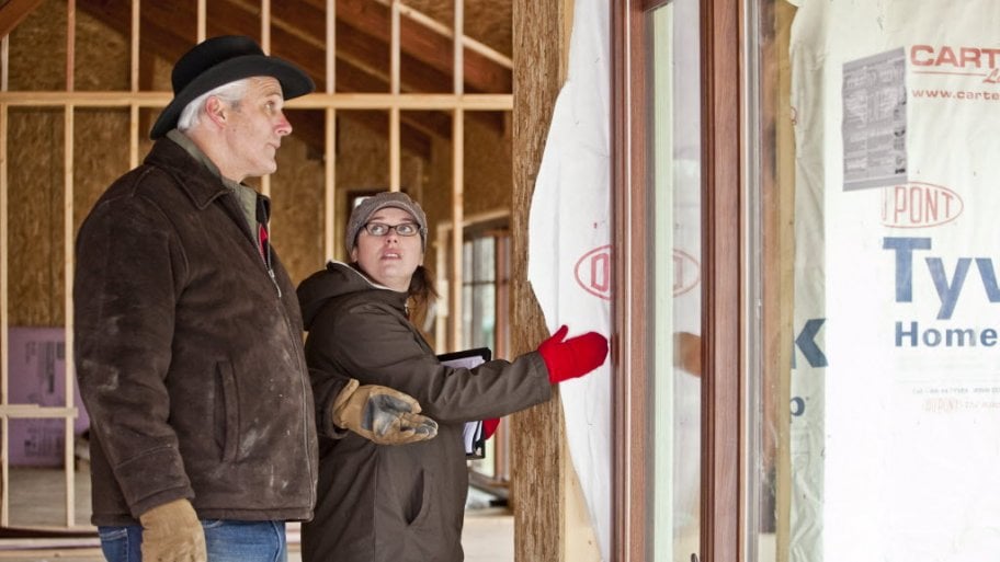 A male homeowner and female LEED verifier look at the inside of a home under construction