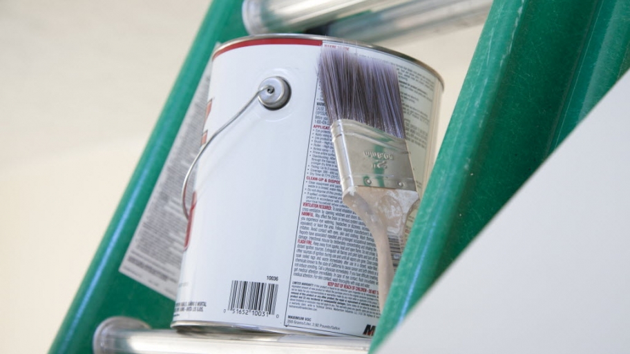 a paint can and brush sitting on a ladder