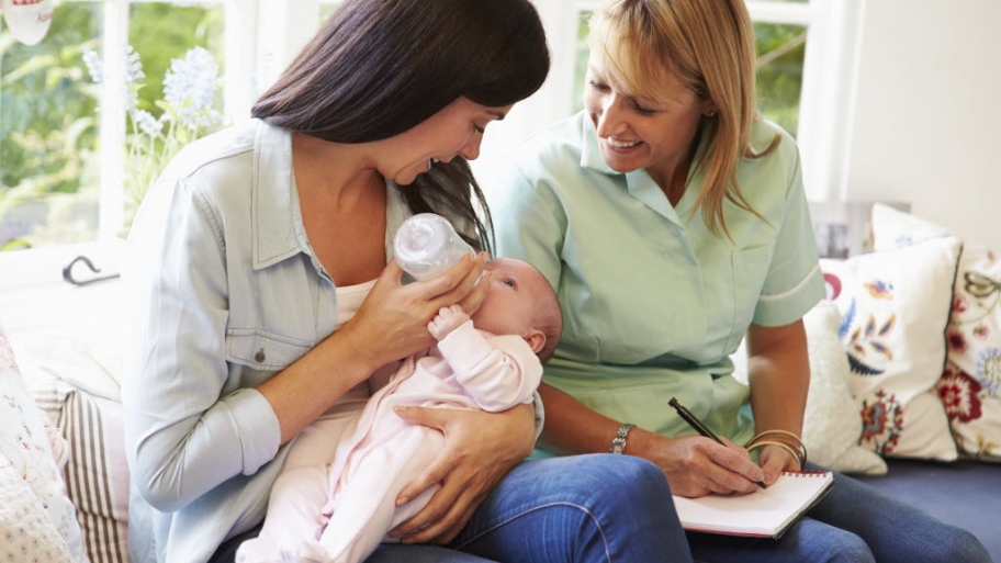 two women feeding a bottle to a baby