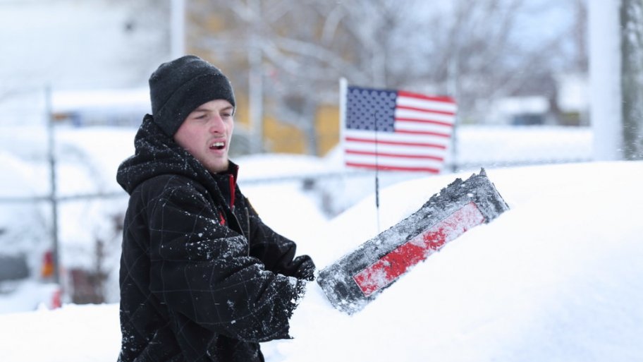 a man shoveling snow off of a car