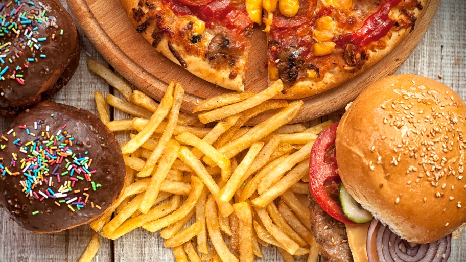 Cupackes, pizza, fries and a burger sit temptingly on a table.