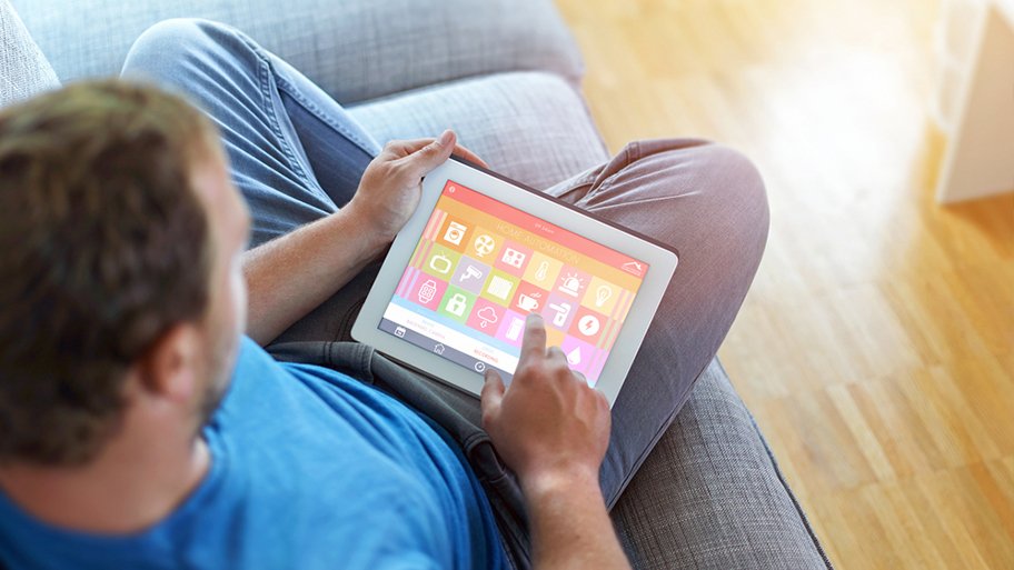 man sitting on couch tapping electronic device