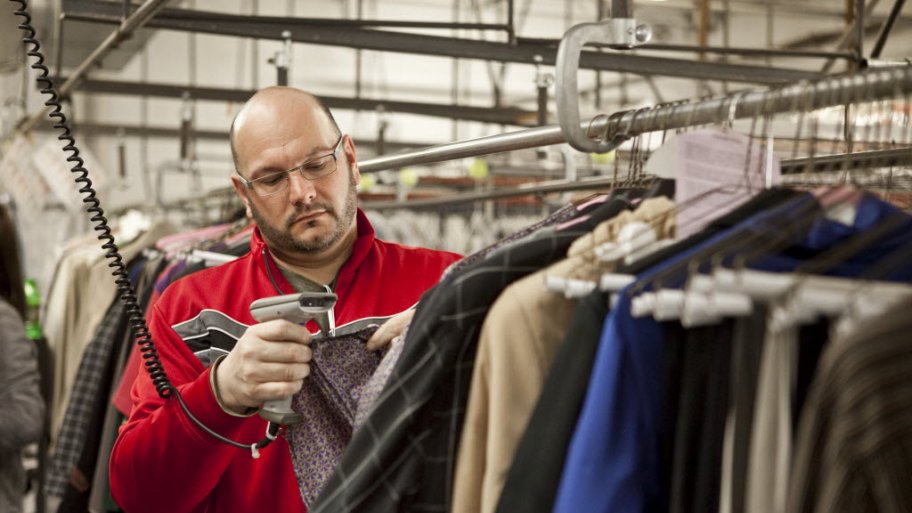man scans clothing tag at a dry cleaner