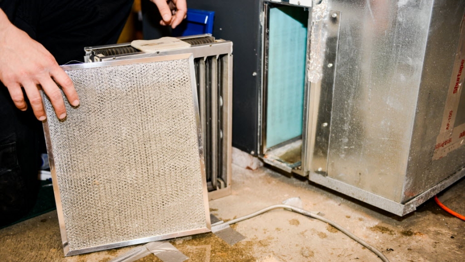 hand holding HVAC filter next to furnace