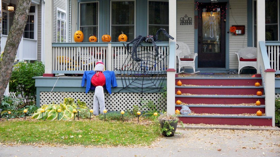 pumpkins, jack-o'-lanterns and a big spider in its web on front porch