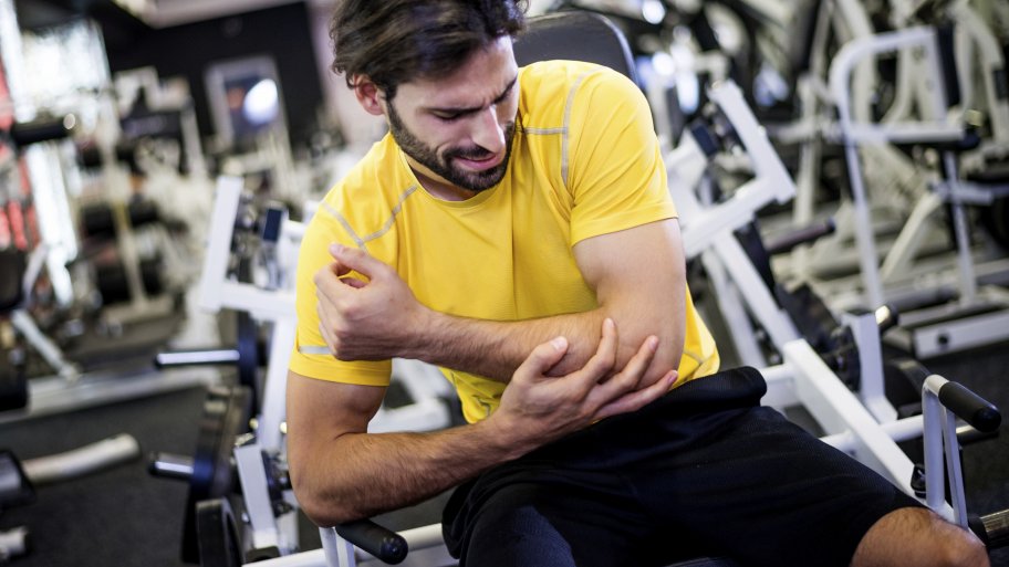 man holding injured elbow in weight room