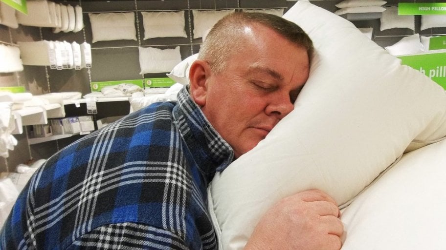A man tests out a pillow at a store display