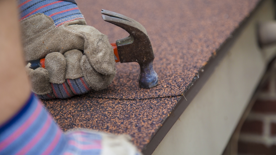 roofer hand nailing asphalt shingles