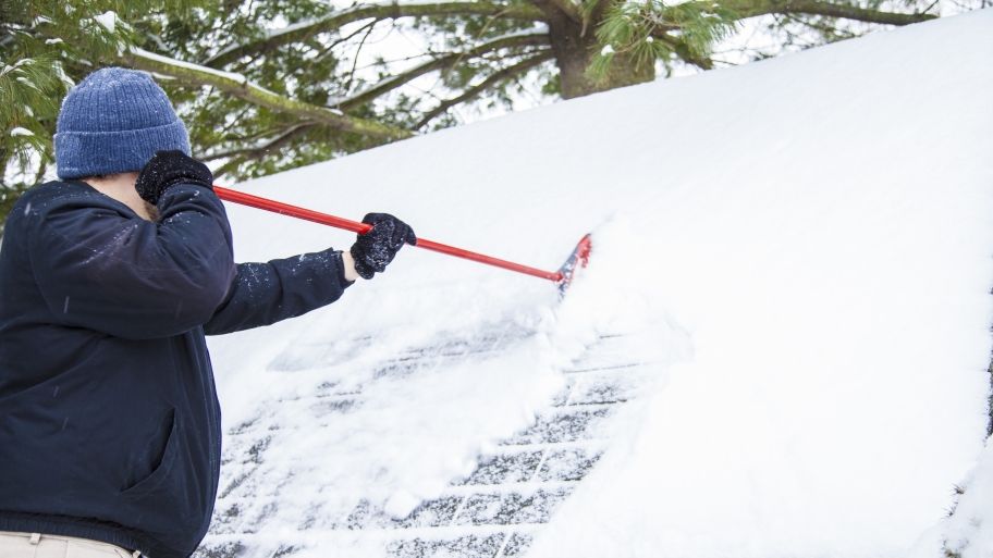 roofer using snow rake on roof