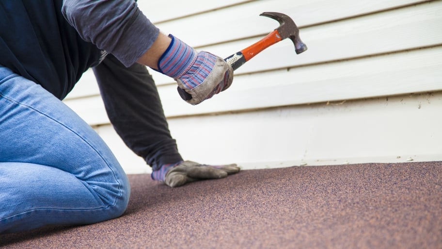 a man works on a roof with a hammer