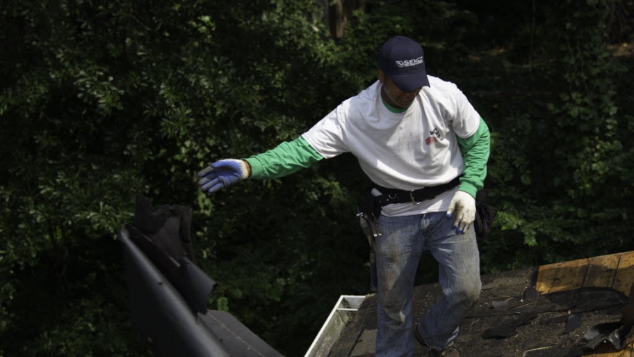 worker clearing off old roof materal