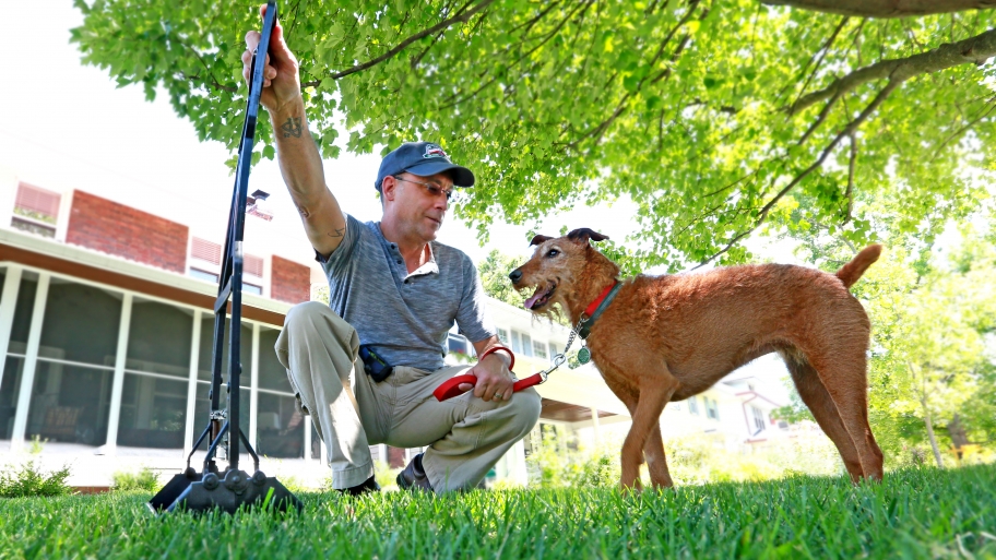man with pooper scooper and dog