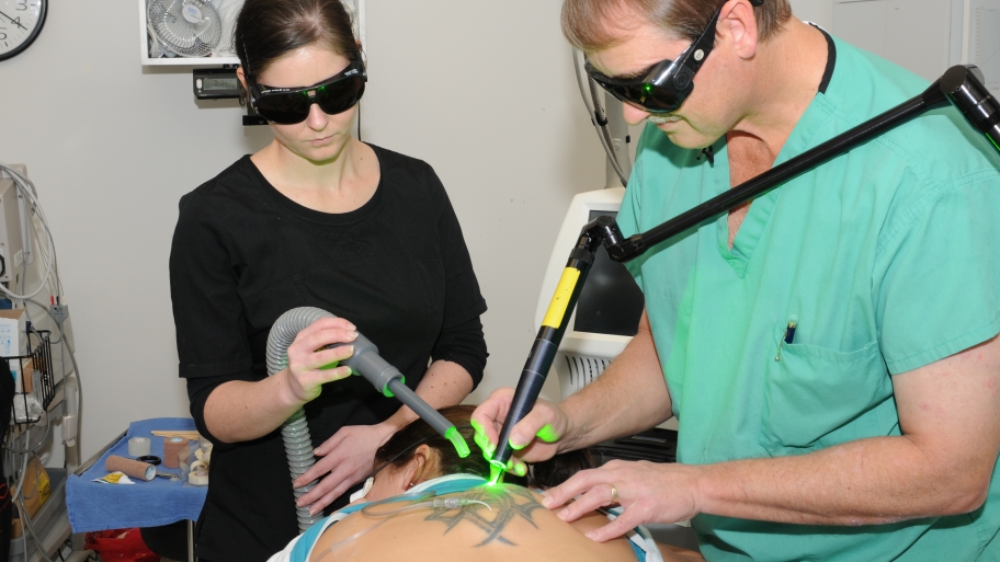 a doctor and assistant remove tattoo with green laser