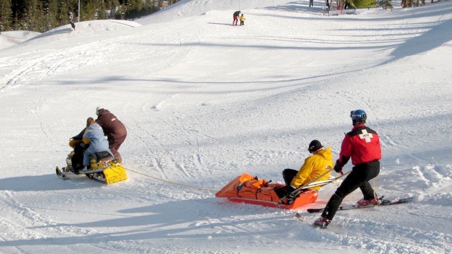 people on skis, sleds on snowy hill