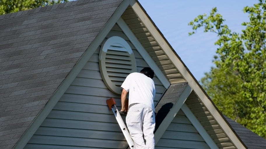 man on ladder painting house