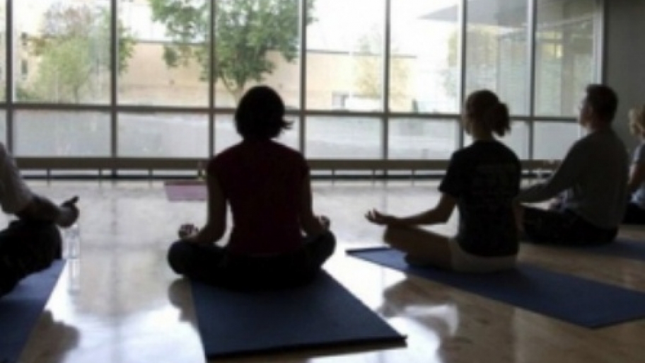 men and women sit crossed legged on the floor to meditation.