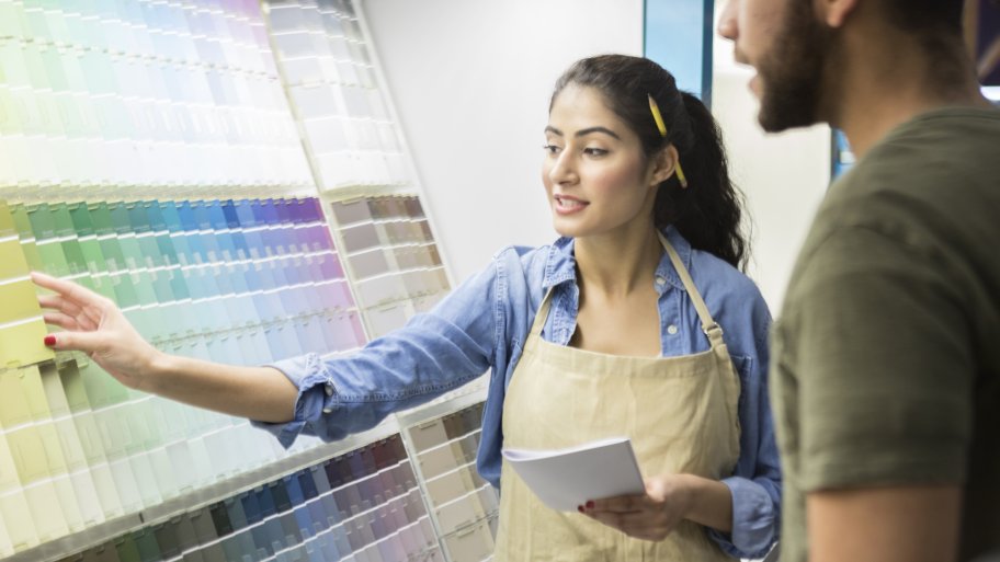 a paint store clerk helps a customer pick a paint color