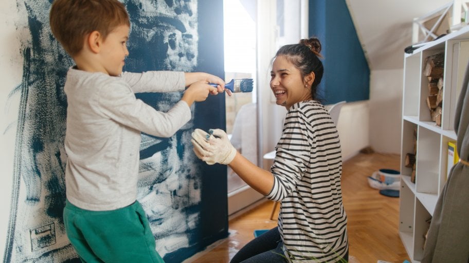 a woman and child painting a wall
