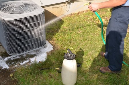 A/C unit being cleaned with soap and hose