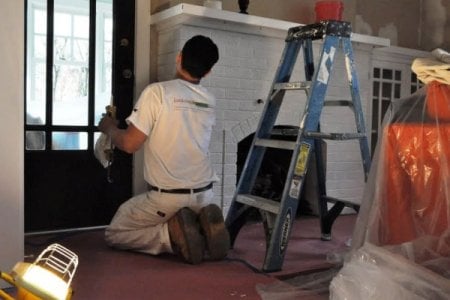 painter brushes paint onto fireplace