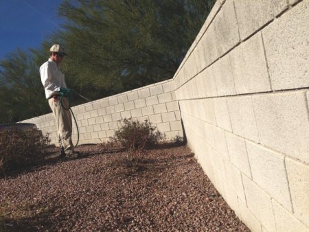 A tech creates a scorpion barrier outside of a Phoenix-area home. Scorpions often live in the cracks of concrete walls. (Photo by Bulwark Exterminating)