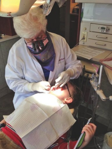 female dentist checks the teeth of a adolescent boy.