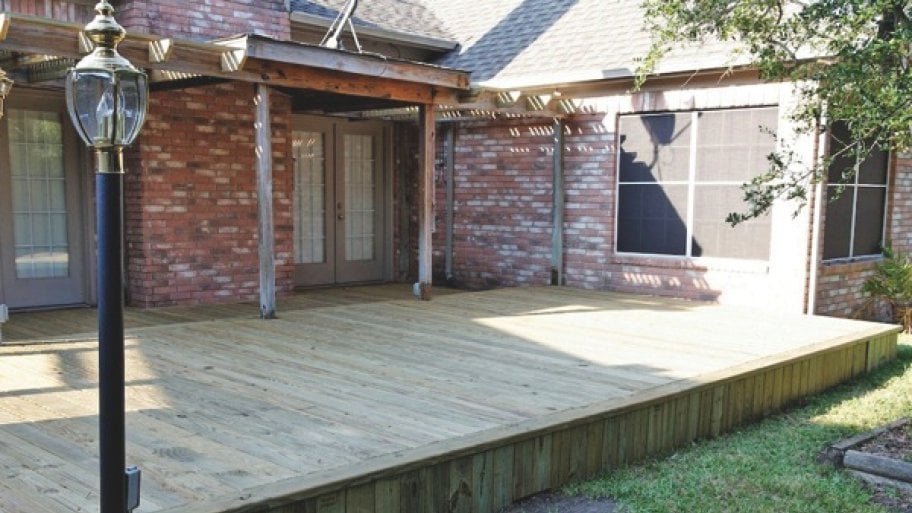 a deck on the backside of a home, with a pergola at the entrance of french patio door.
