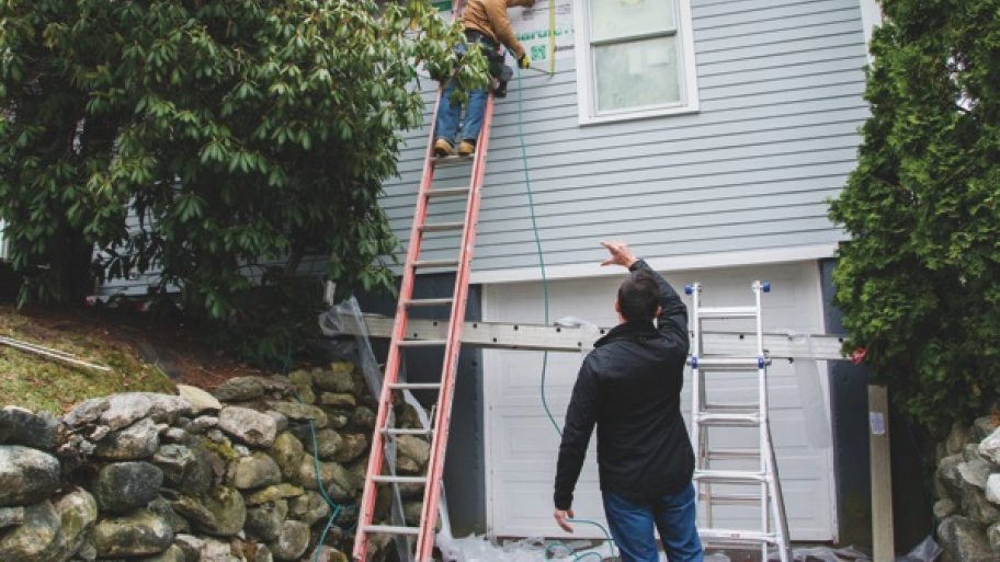 contractor supervises siding installation during home remodeling project