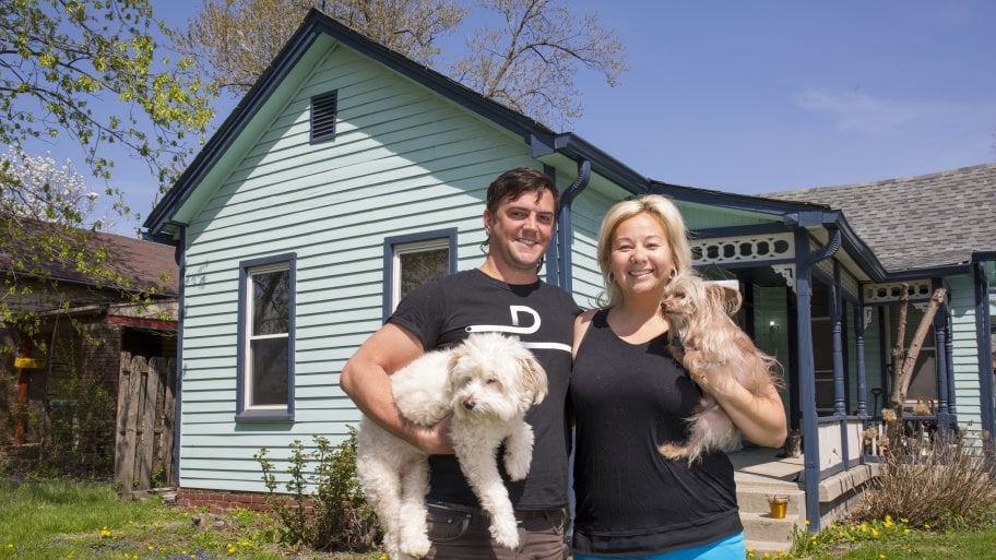Angie’s List Members Tad and Amity Aschliman holding their dogs, Champ and Nuni, in front of their Fountain Square home.