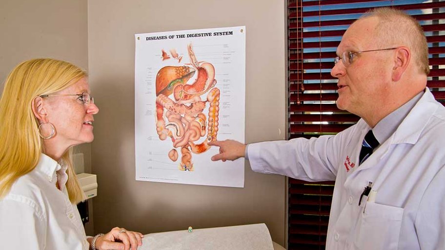 a doctor points to an illustration of a digestive system while talking to a female patient