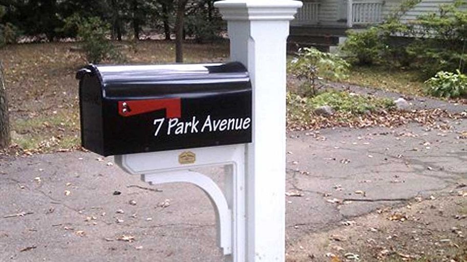 black mailbox on white wooden post