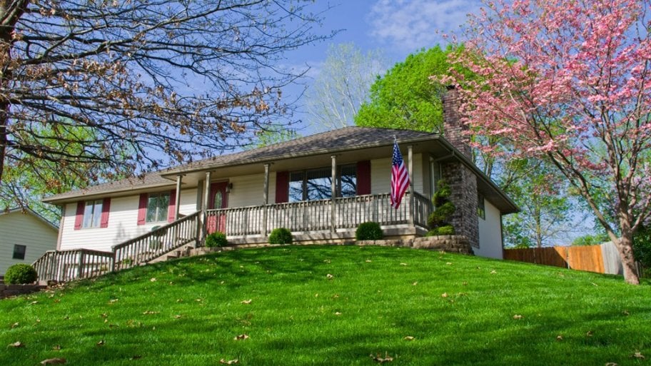 one-story home on a hill with green lawn